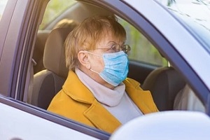 old lady in car wearing mask during Senior Transportation Service